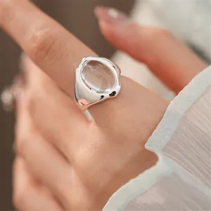 Primo piano di un anello d'argento minimalista aperto con una pietra ovale in vetro.