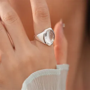Vista dettagliata di un anello d'argento minimalista con pietra di vetro ovale su un dito