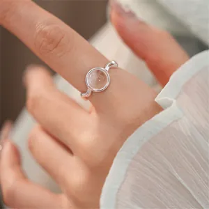 Primo piano di un anello ovale in vetro minimalista al dito con elegante fascia argento.
