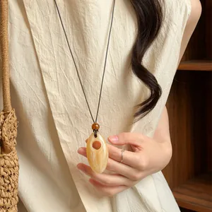 Detailed view of a vintage marbled amber pendant necklace on a beige linen dress.