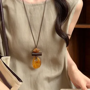 Close-up of retro long necklace with amber-like pendant and wood detail on model