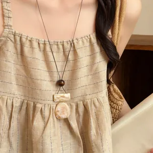 Detail of vintage New Chinese style necklace with marble textured pendant on linen dress.
