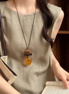 Detailed view of a retro resin pendant necklace styled with a linen outfit