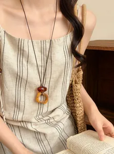 Close-up of vintage resin pendant necklace on long cord styled with a linen dress