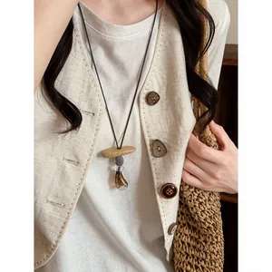 Detailed view of a vintage Zen style long pendant necklace worn with a linen vest outfit