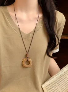 Detailed view of a vintage long necklace with a round amber pendant and woven frame.
