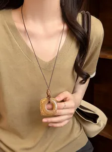 Vintage long necklace with translucent pendant styled on a beige knitted top detail