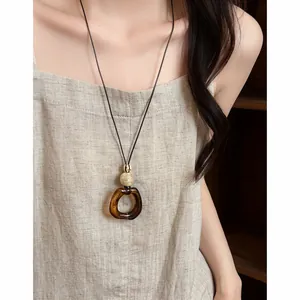 Elegant retro long necklace with amber swirl pendant and gold bead worn on linen dress
