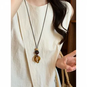 Detailed view of an elegant retro amber resin pendant hanging from a long black cord.