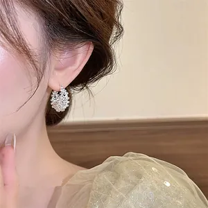 Primo piano di un orecchino a cerchio a cesto di fiori traforato in argento indossato.