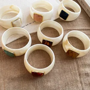 Elegante set di larghi bracciali in acrilico con dettagli in pietre colorate su lino