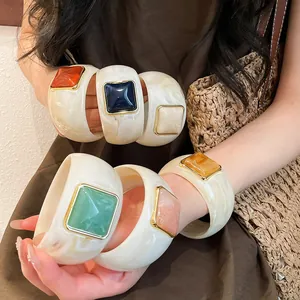 Dettaglio di bracciali rigidi in acrilico con vivaci pietre quadrate in resina colorata