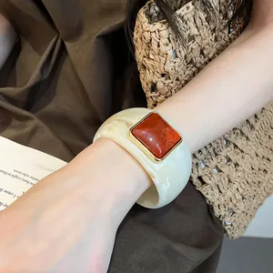 Primo piano di un ampio bracciale in acrilico marmorizzato con pietra arancio