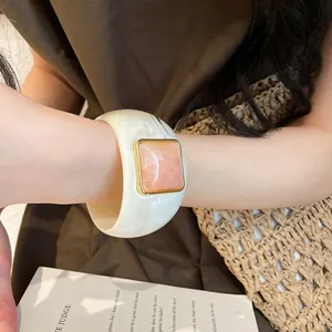 Primo piano dettagliato di un ampio bracciale in acrilico crema con centro in marmo rosa
