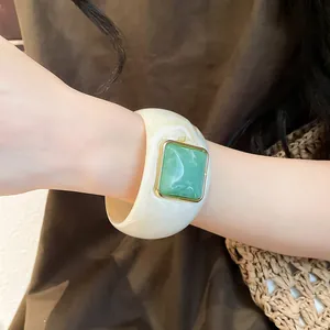 Dettaglio di un ampio bracciale in acrilico marmo bianco con un inserto quadrato verde