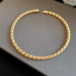 Macro detail of a vintage twisted metal choker with a gold-tone finish and open design.