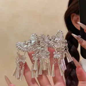 Gros plan sur des pinces à cheveux ethniques argentées avec motifs d'oiseaux et glands.
