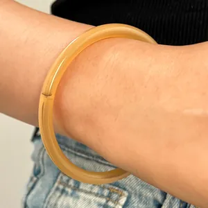 Primer plano de un brazalete de resina translúcida caramelo en la muñeca, estilo chino.