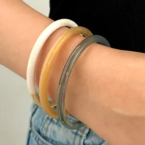 Detalle de tres pulseras apilables de resina imitación jade en color crema y ámbar