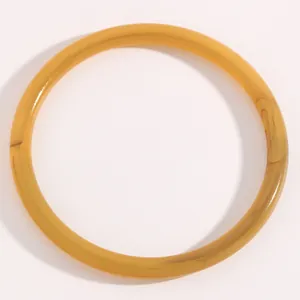 Brazalete minimalista de resina de caramelo translúcida con un perfil fino y sutil.