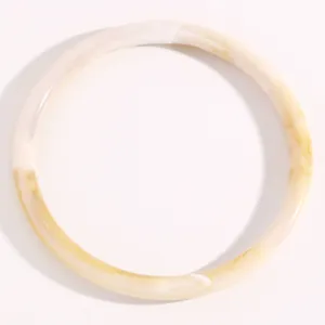 Primer plano de un brazalete de resina translúcida con efecto mármol blanco y caramelo