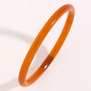 Primer plano de un brazalete de resina de color caramelo con textura suave y brillo cálido.