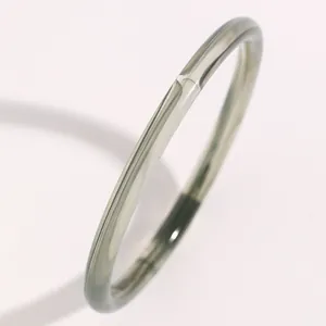 Primer plano de un brazalete fino de resina verde grisáceo traslúcido y liso