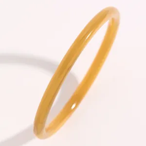 Primer plano detallado de una fina pulsera de resina translúcida color caramelo estilo jade