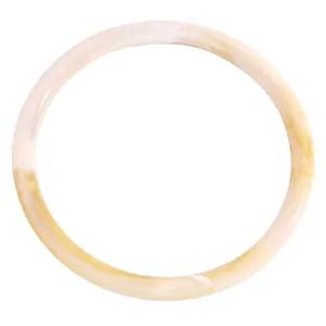 Primer plano de un brazalete fino de resina con textura veteada en blanco hielo y caramelo