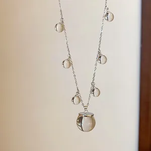 Vista detallada de un collar minimalista con colgantes esféricos de resina clara