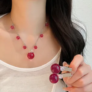 Primer plano de un conjunto de collar y pinzas para el cabello de resina roja en modelo.