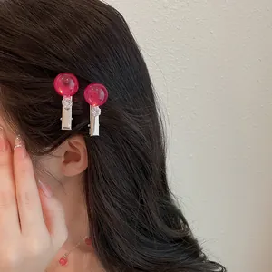 Vista detallada de dos pinzas para el cabello de resina rosa con cristales en el pelo.