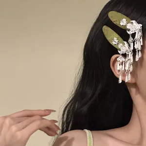 Detailed view of traditional Chinese style hair clips with silver bell tassels on model