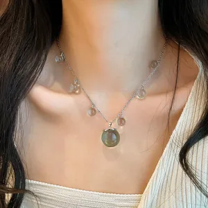 Primer plano detallado de un collar de cuentas de resina translúcida, cadena plateada