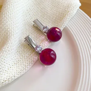 Vista macro detallada de dos pinzas para el cabello de resina magenta con cristales brillantes