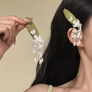 Close-up detail of silver Guofeng hair clips with bell tassels worn on model's hair