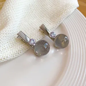 Detalle de elegantes pinzas para el cabello con esferas de resina gris y piedras.