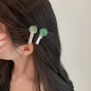 Primer plano de elegantes pinzas para el cabello de resina verde hielo en cabello oscuro