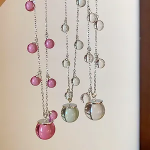 Detalle de collares de cuentas de resina translúcida en rosa y verde con cadenas plateadas.