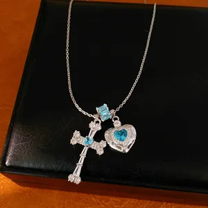 Close-up detail of a silver necklace featuring blue zircon heart and cross-shaped pendants.