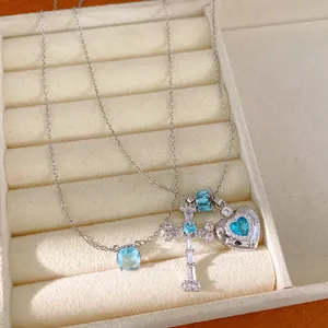 Close-up of blue zircon necklace with cross and heart pendants in a jewelry tray.