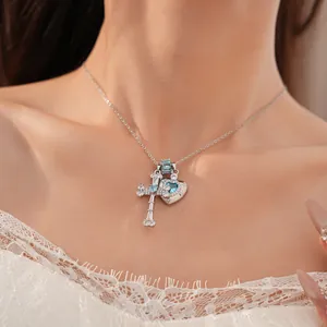 Detail shot of silver cross and blue heart zircon pendant necklace worn on neck