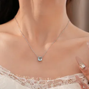 Close-up detail of a square light blue zircon necklace worn by a model in white lace