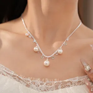 Close-up of an elegant pearl necklace with zircon tassels and a delicate lace-style chain