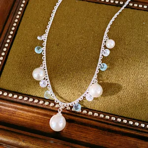 Elegant silver lace necklace featuring pearls and blue zircon on a green velvet box