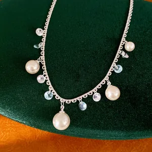 Close-up detail of an elegant silver tassel necklace featuring pearls and sparkling zircon charms