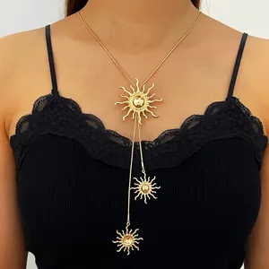 Detailansicht einer goldenen Sonnenquasten-Halskette an einem Model mit schwarzer Spitze.