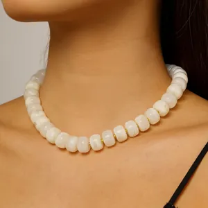 Close-up of elegant white barrel-beaded choker necklace with gold spacers on model