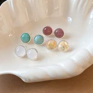 Close-up of vintage round agate stud earrings in various pastel colors inside a shell