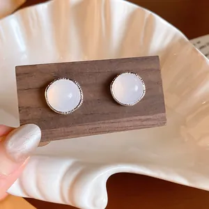 Close-up of retro silver earrings with milky white agate stones on wood